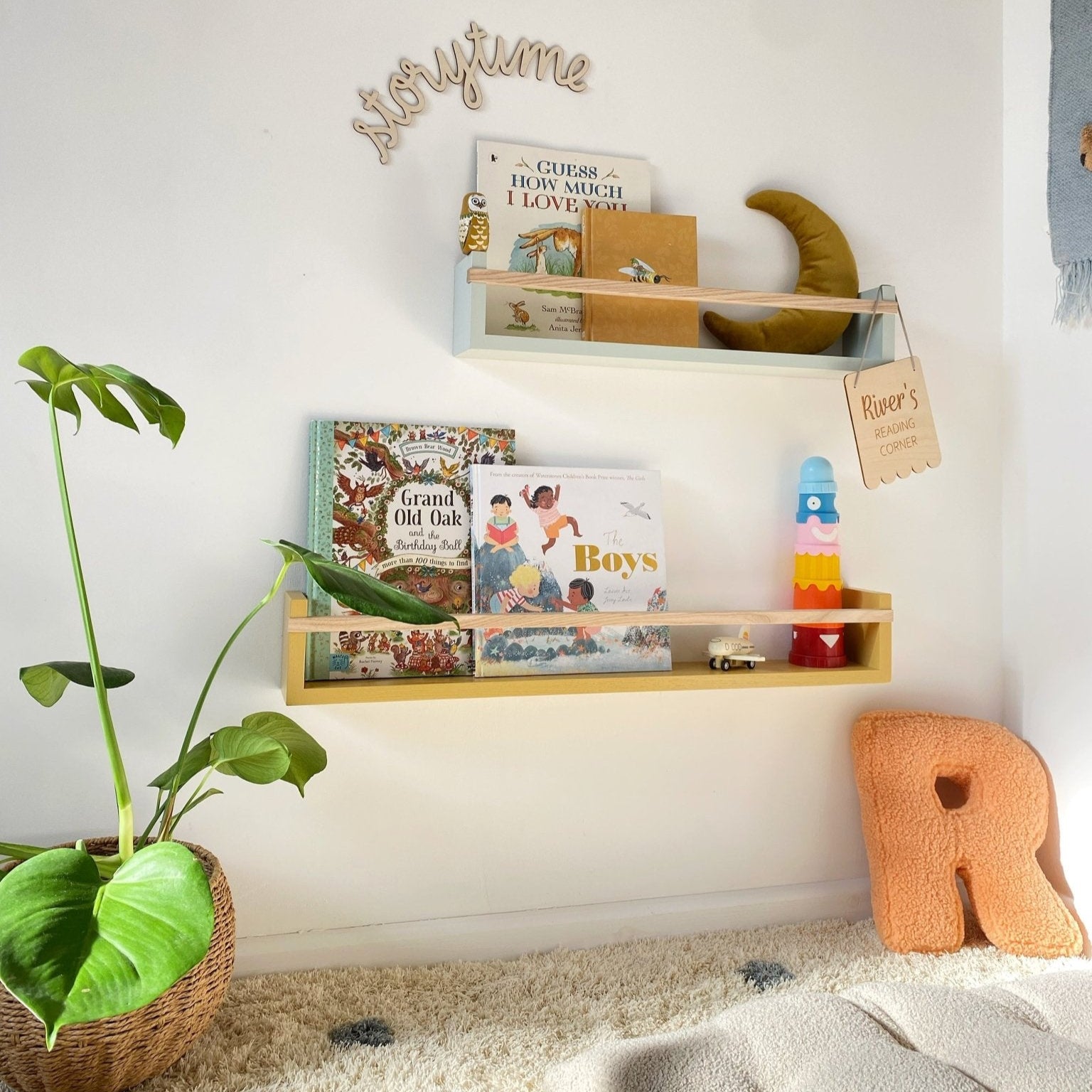 Children's room with a shelf displaying books and toys, a plant, and a decorative letter 'R'.