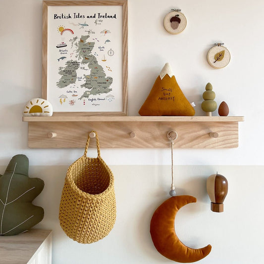 Wooden shelf with decorative items including a framed map, plush toys, and hanging baskets against a light wall.