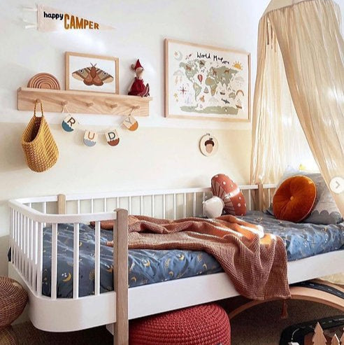 Children's bedroom with a white crib, wooden shelf, and decorative elements.