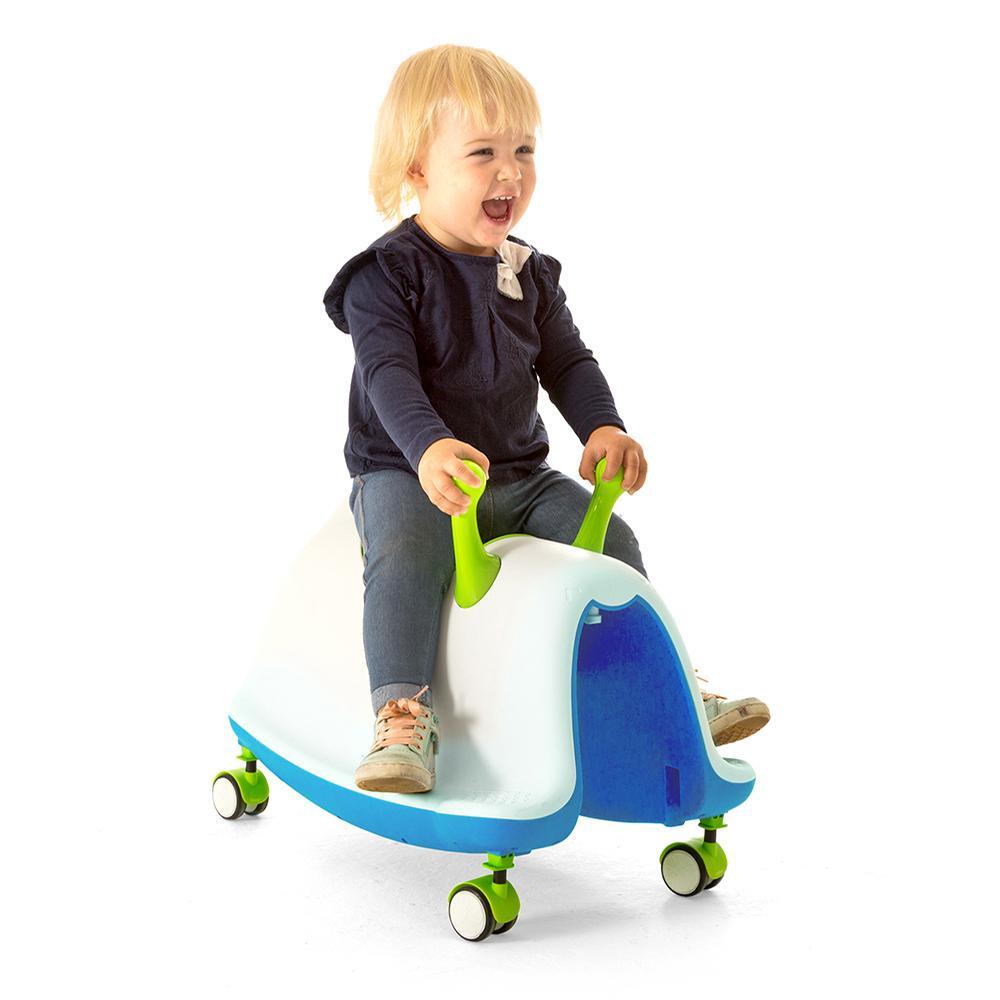 Child riding a blue and green toy vehicle on a white background