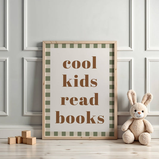 Framed poster with 'cool kids read books' text on a checkered background, placed on a wooden floor with a plush toy and blocks.