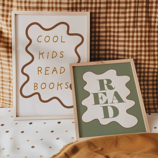 Two framed signs on a checkered fabric background, one with 'Cool Kids Read Books' and the other with 'READ'.