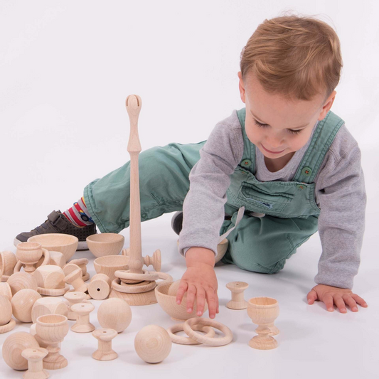 Child playing with wooden loose parts toys on a white background