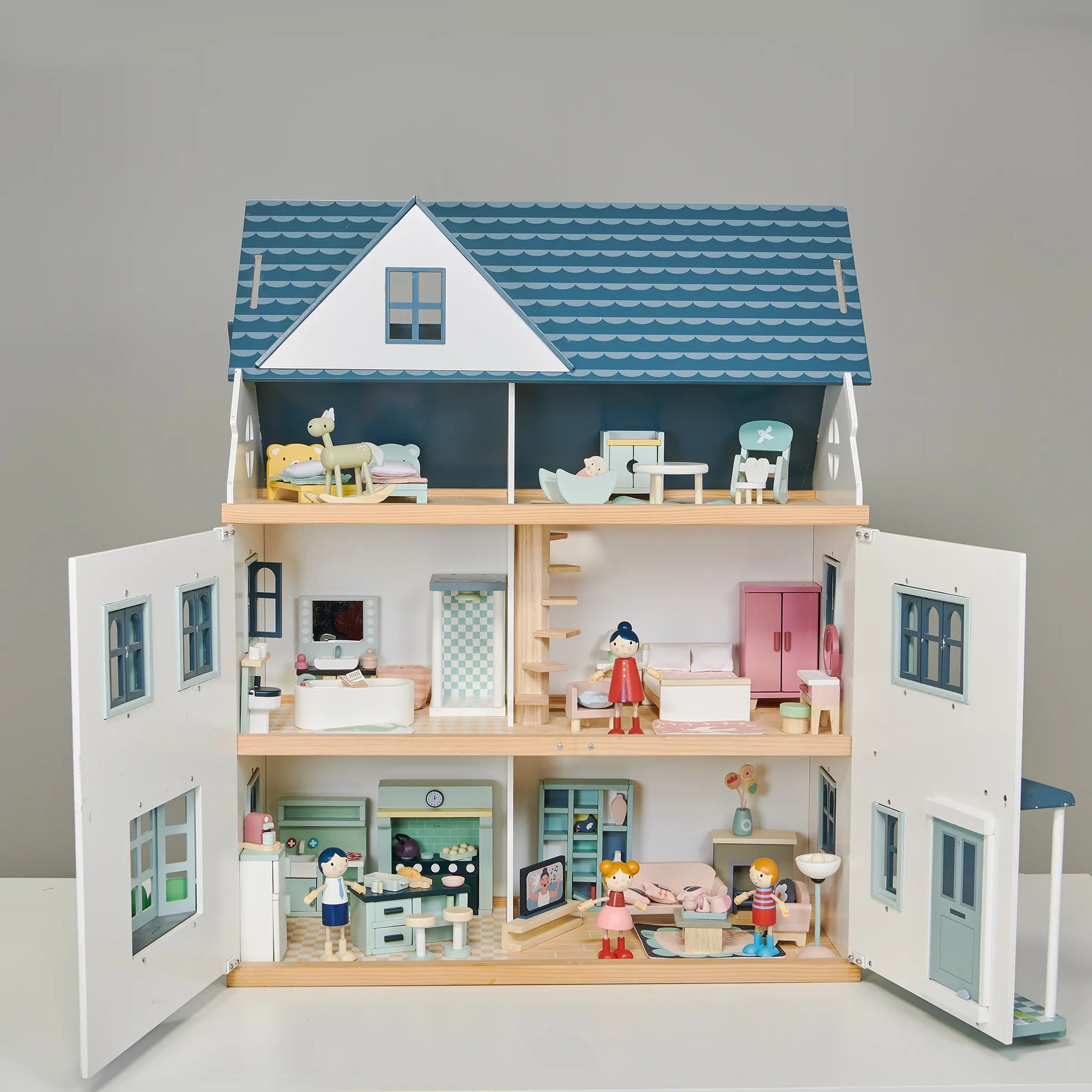Wooden dollhouse with open doors showing different rooms and furniture on a gray background