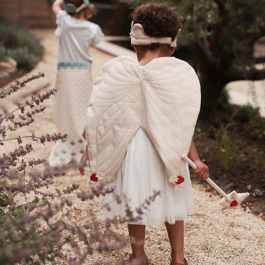 Child in angel costume with wings standing in a garden with lavender.