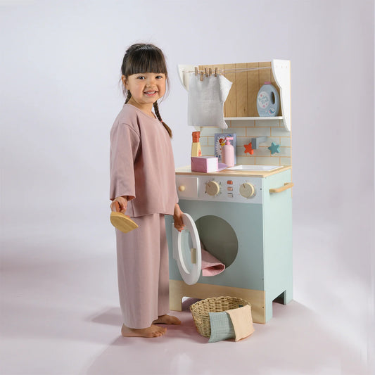 Child playing with a toy washing machine and dryer set on a plain background