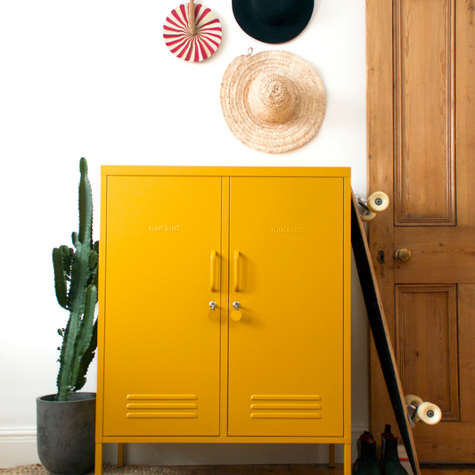 Yellow cabinet in a room with a wooden door, rug, and decorative items.