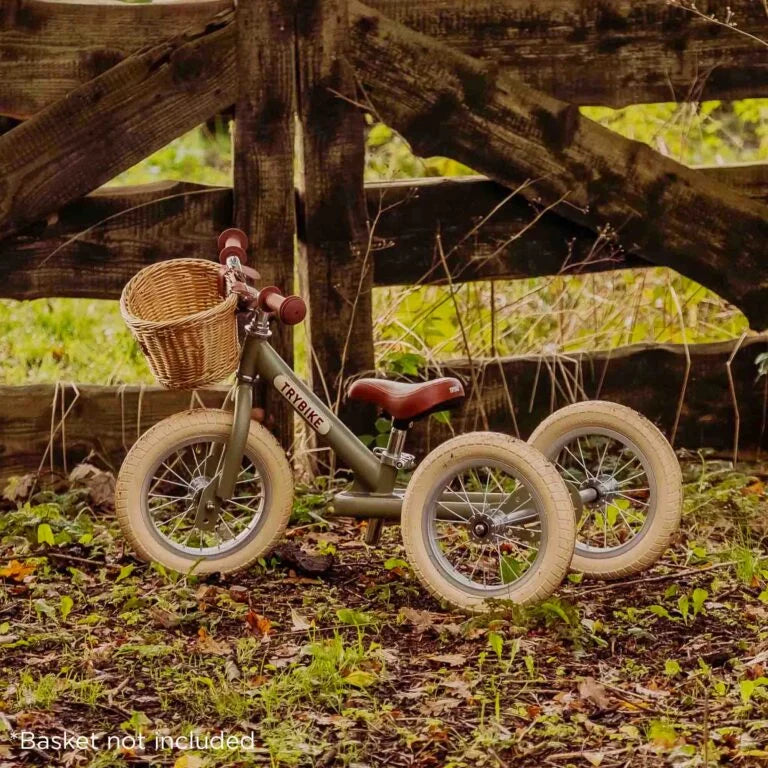 Children's balance bike with basket against a wooden fence in a natural setting
