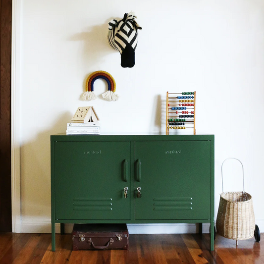 Green metal cabinet against a white wall with decorative items on top