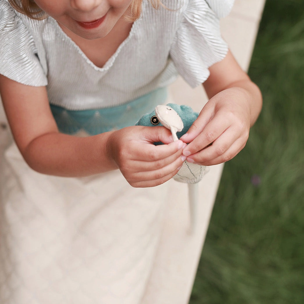 Child holding a small white creature with a blurred green background