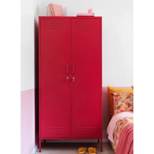 Red metal cabinet in a room with a bed and colorful bedding.