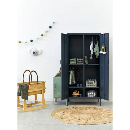 Nursery with open dark blue wardrobe, wooden crib, and round rug.
