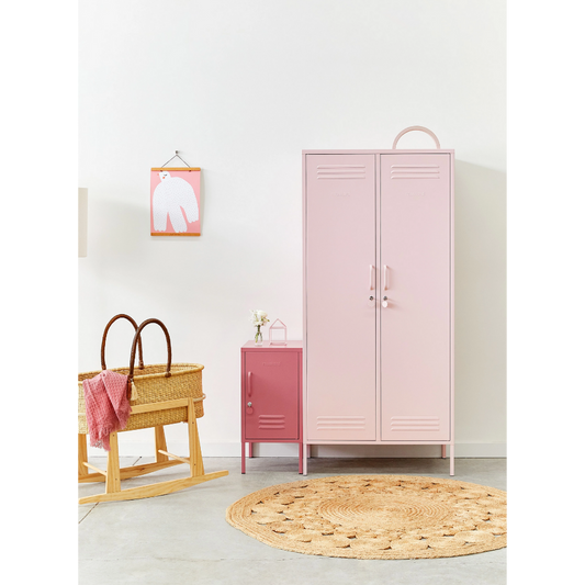 Pink locker in a room with a wooden basket and round rug on a light gray floor.
