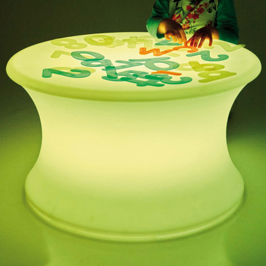 Children's sensory table with glowing numbers and letters on a dark background