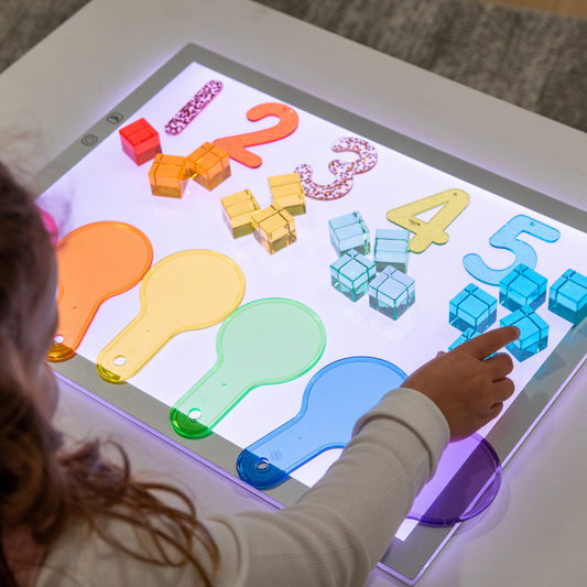 Child interacting with a colourful light panel displaying numbers and shapes.
