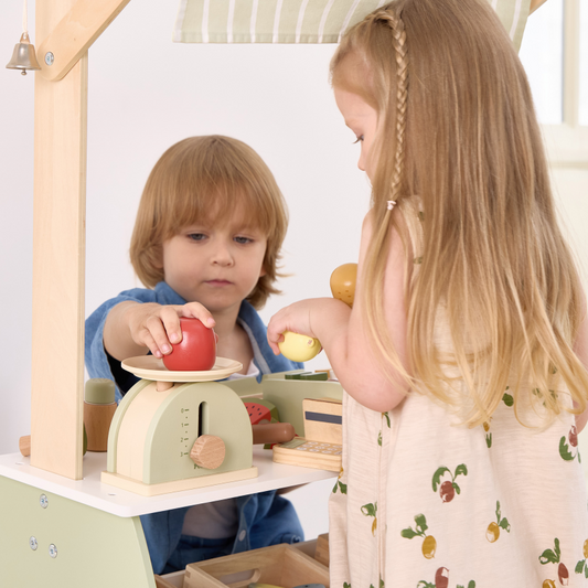 Two children playing with a wooden toy kitchen set.