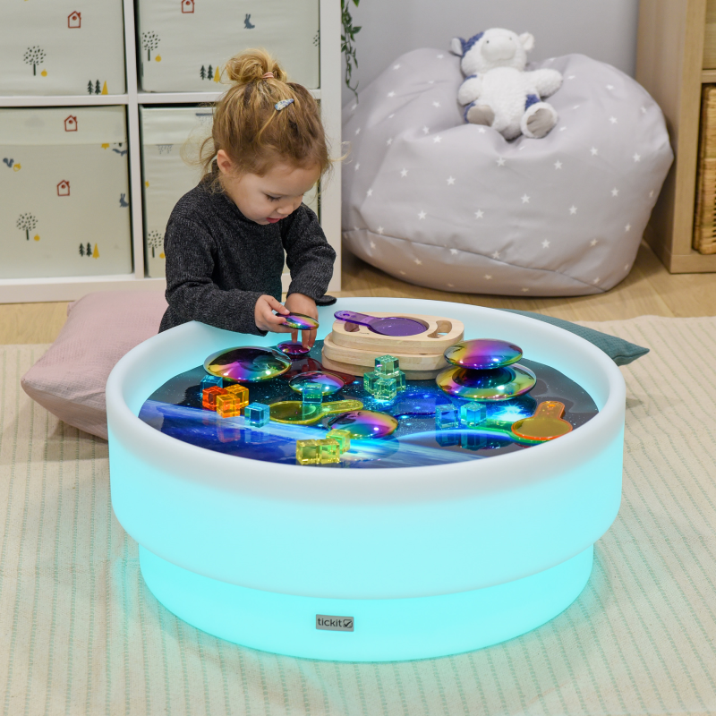 Child playing with a colorful LED play table in a room.