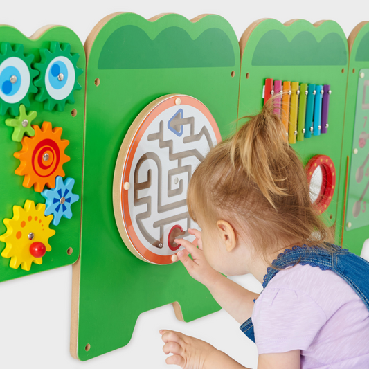Child playing with a colourful educational toy panel featuring gears and a maze.