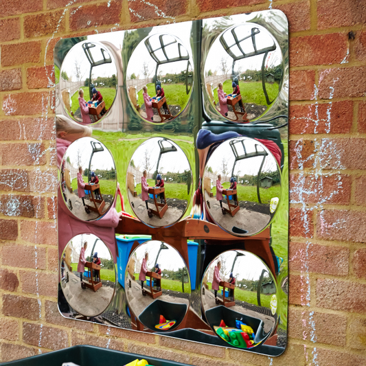 Multiple convex mirrors on a brick wall reflecting outdoor scenes.