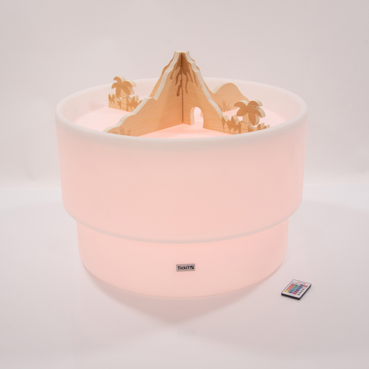 Sensory Play table in a red glow light with wooden jurassic volcano dividers