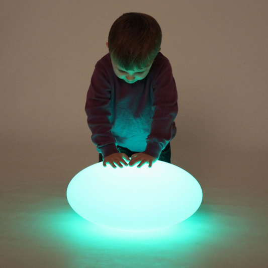 A child standing over a pebble shaped light.