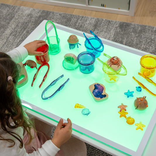 Child playing with colourful toys on a light-up panel