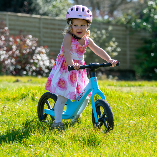 Child riding a balance bike in a garden
