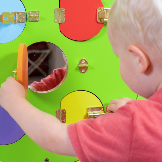 Child playing with a colourful puzzle board shaped like a caterpillar featuring various shapes and colors.