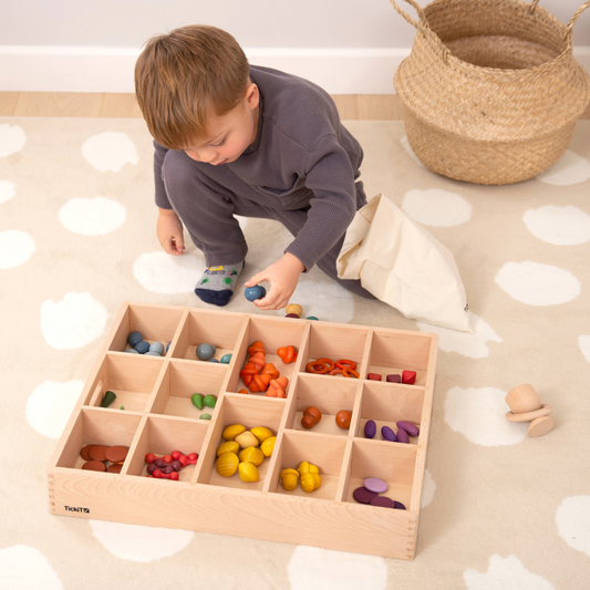 Child playing with a wooden sorting toy on a patterned floor.