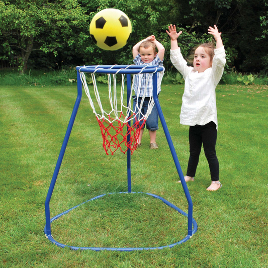 Two children playing with a basketball hoop and ball in a grassy area.