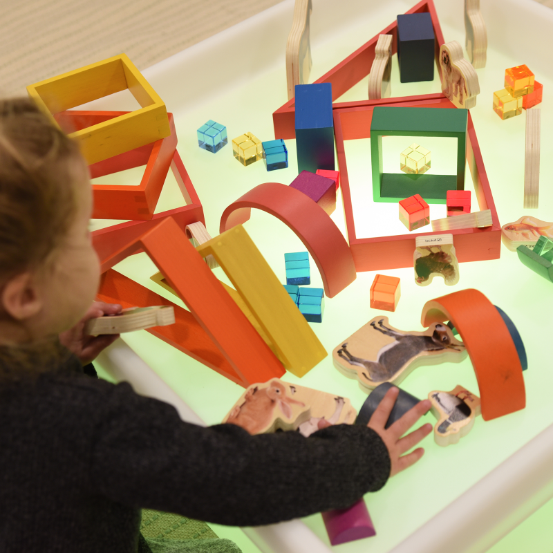 Child playing with colorful wooden toys on a light surface