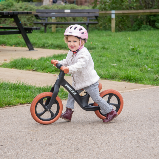 Child riding a balance bike in a park