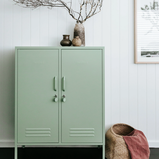 Green metal cabinet with decorative elements against a white wall.