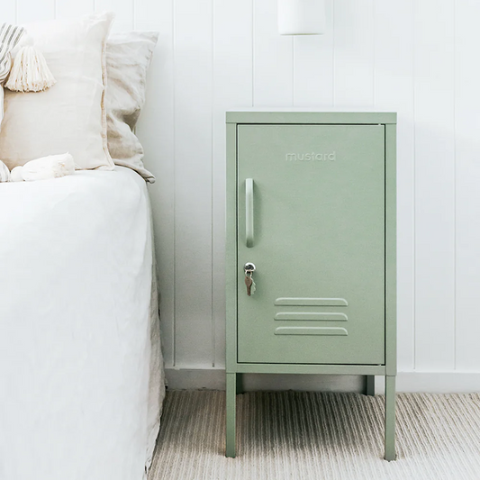 Green metal locker against a white wall in a bedroom setting