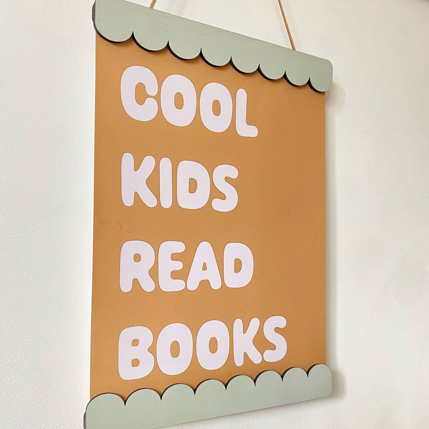 Decorative sign with 'Cool kids read books' text on a plain background