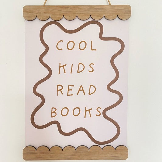 Decorative sign with 'Cool kids read books' text on a plain background