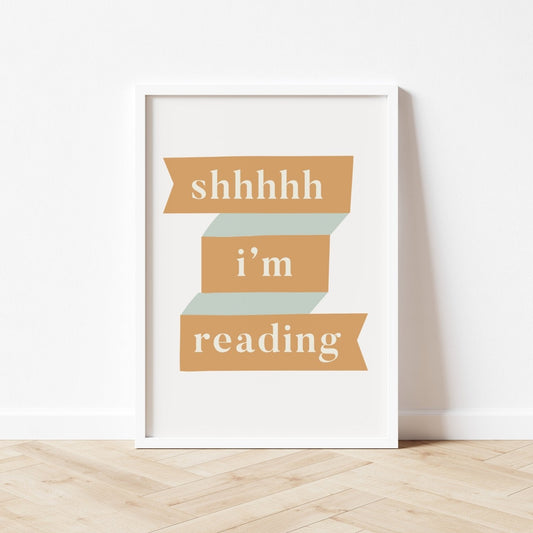 Framed print with 'shhhh i'm reading' text on a white wall.