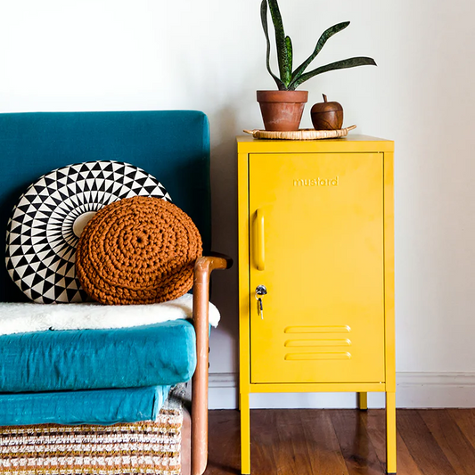 Yellow cabinet with a plant next to a blue chair on a wooden floor.