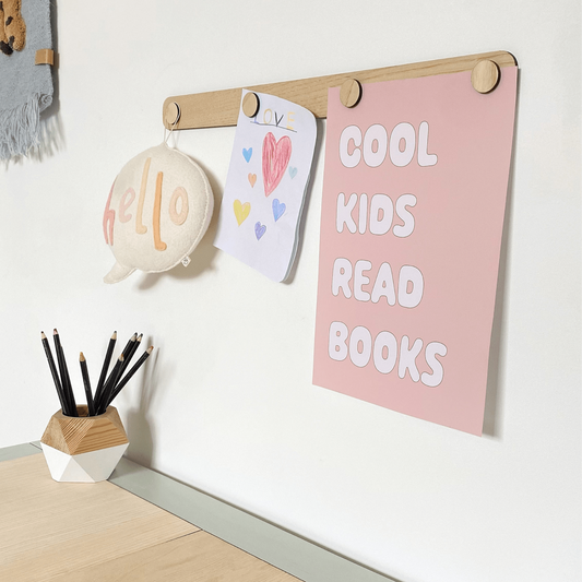 Wall with a motivational poster, children's art, and stationery items in a child-friendly room.