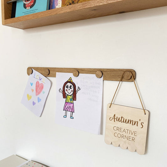 Children's artwork and a sign on a shelf with books in the background