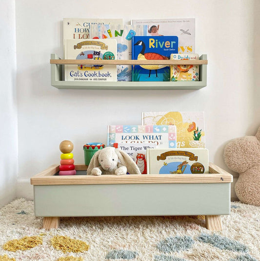 Green toy box with teddy bear, books, and abacus on a carpeted floor.