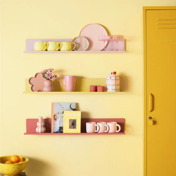 Shelves with decorative items against a yellow wall with a mustard-colored locker.