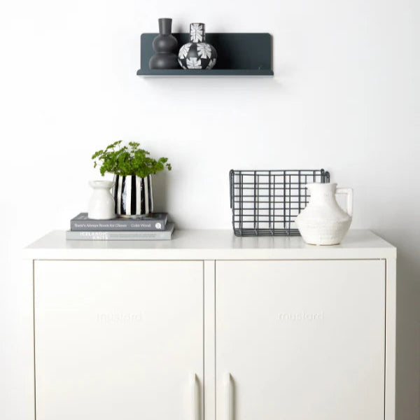 White cabinet with decorative items including a plant, basket, and bottles on a white background