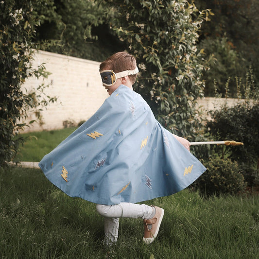 Child in a blue cape and superhero mask outdoors